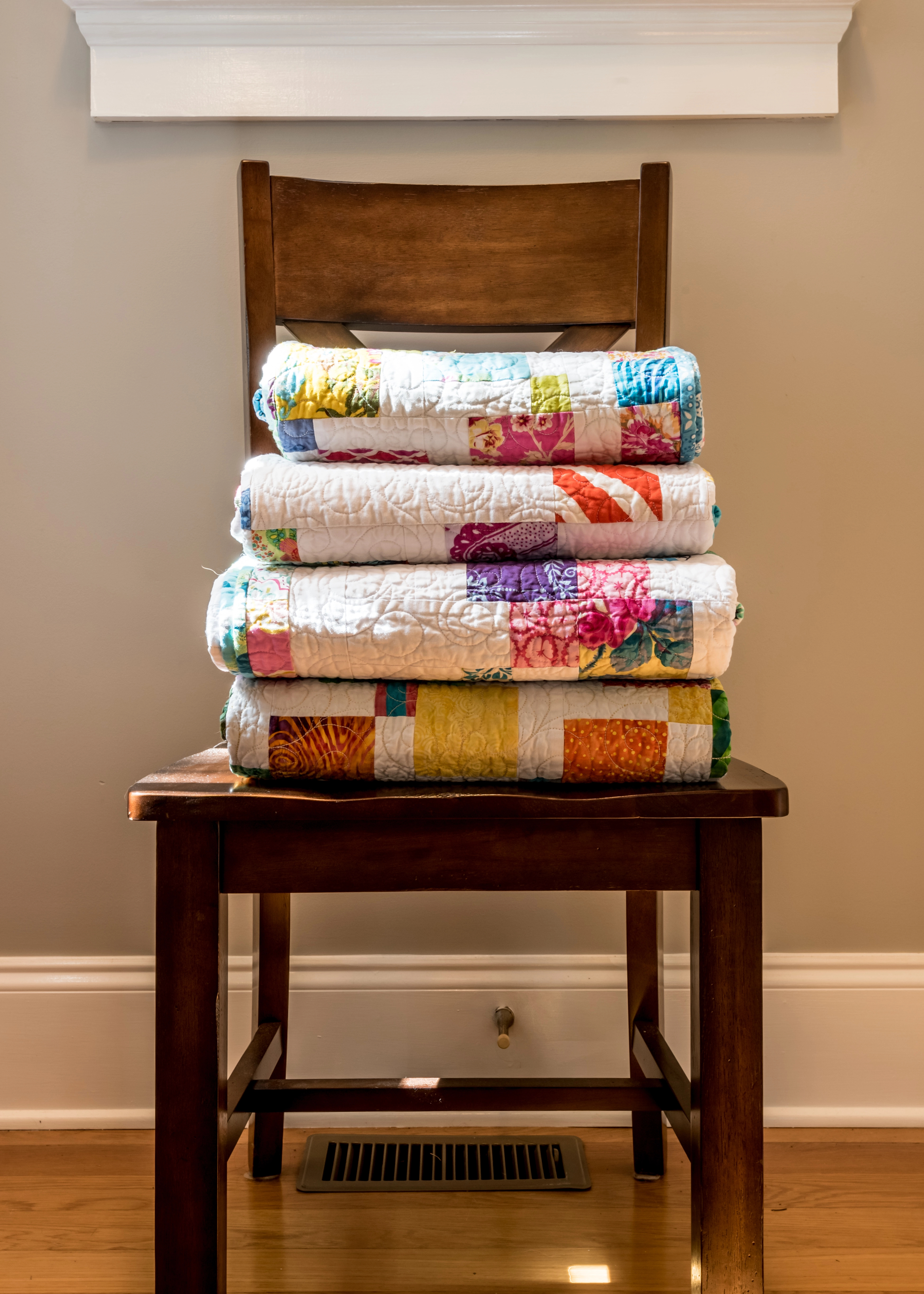Depositphotos_172528354_XL A stack of folded, colorful quilts on a brown, wooden chair – Your quilt doesn't have to be perfect